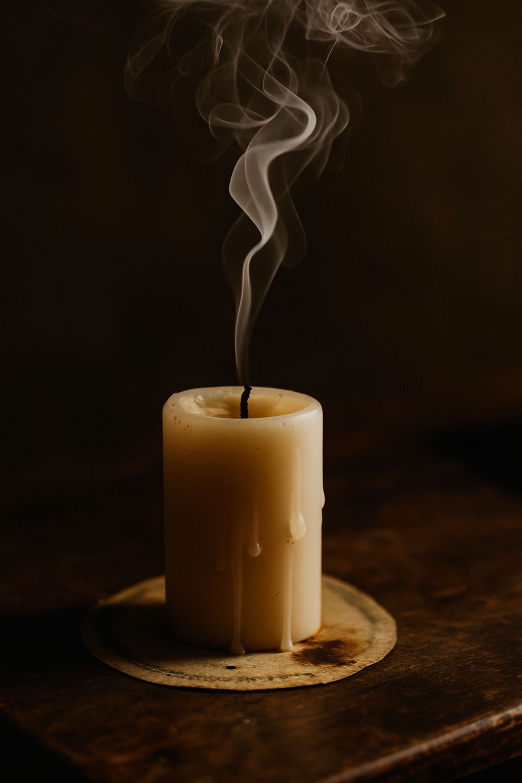 Extinguished masculine candle trailing smoke in dim light